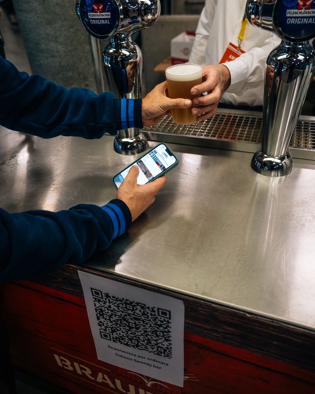 A phone beside the QR code on a bar counter, beer taps behind.