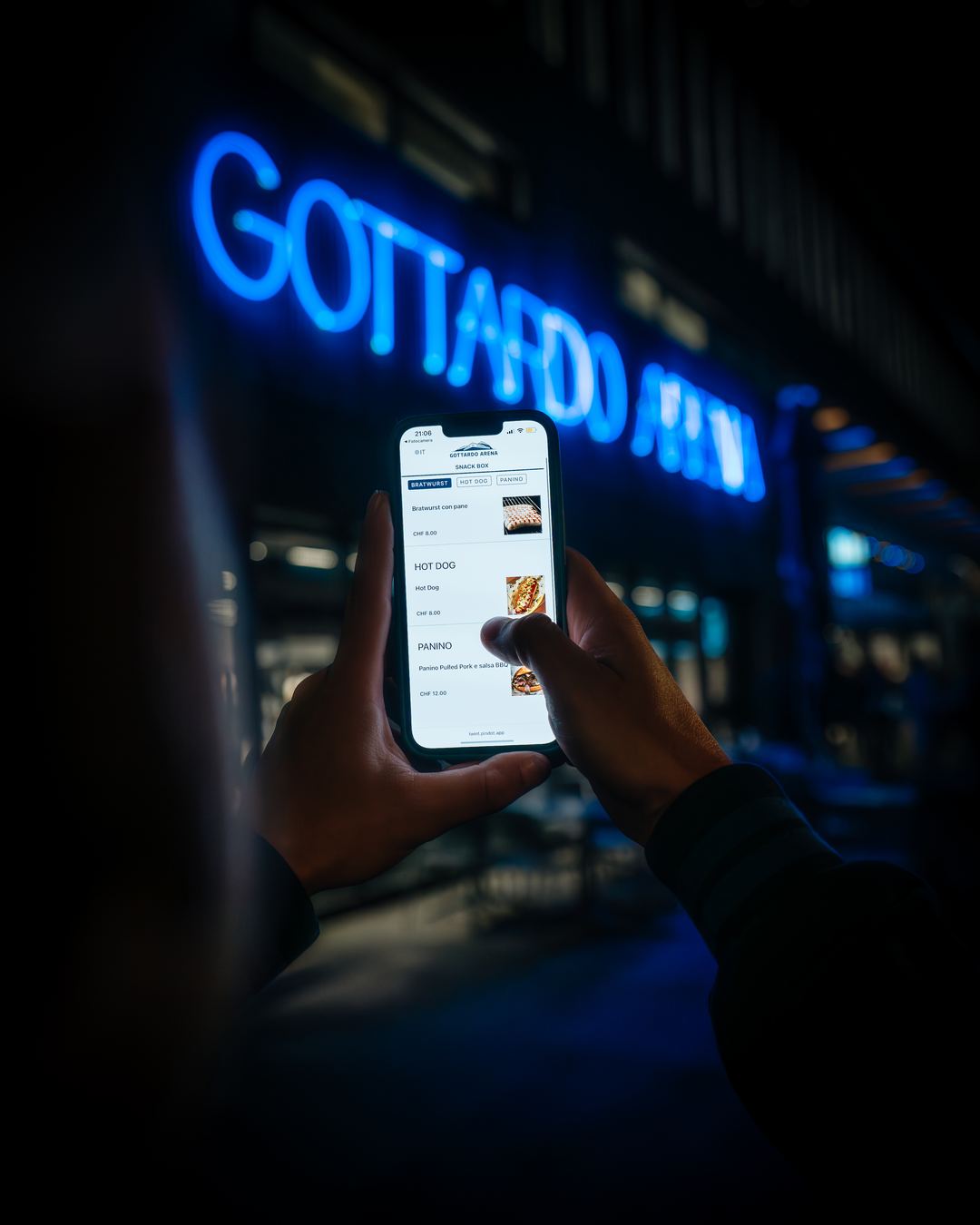 A phone showing the ordering page outside the arena at night.