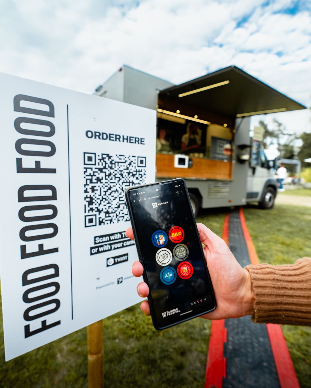 Ein Handy mit der Bestellseite vor einem Foodtruck.