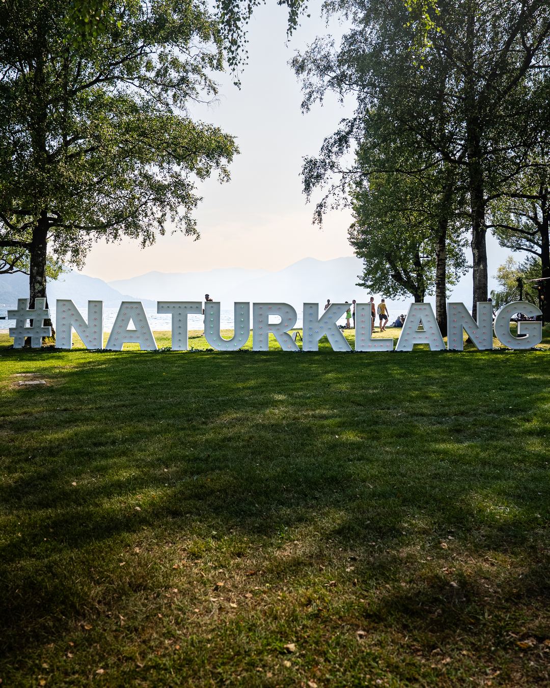 The Naturklang festival lettering standing in a lakeside park.