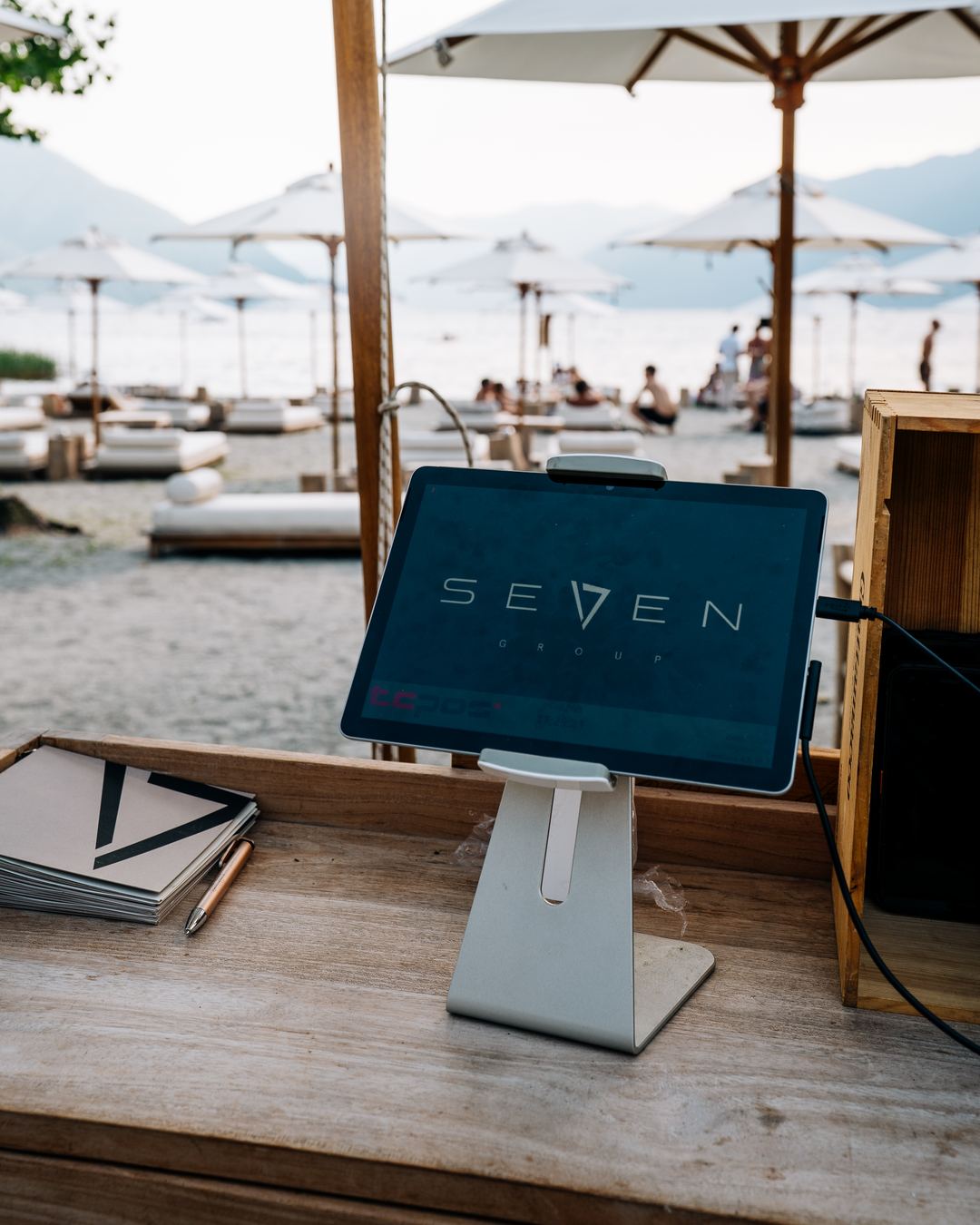 A Seven self-service terminal on a wooden counter, the lake behind it.