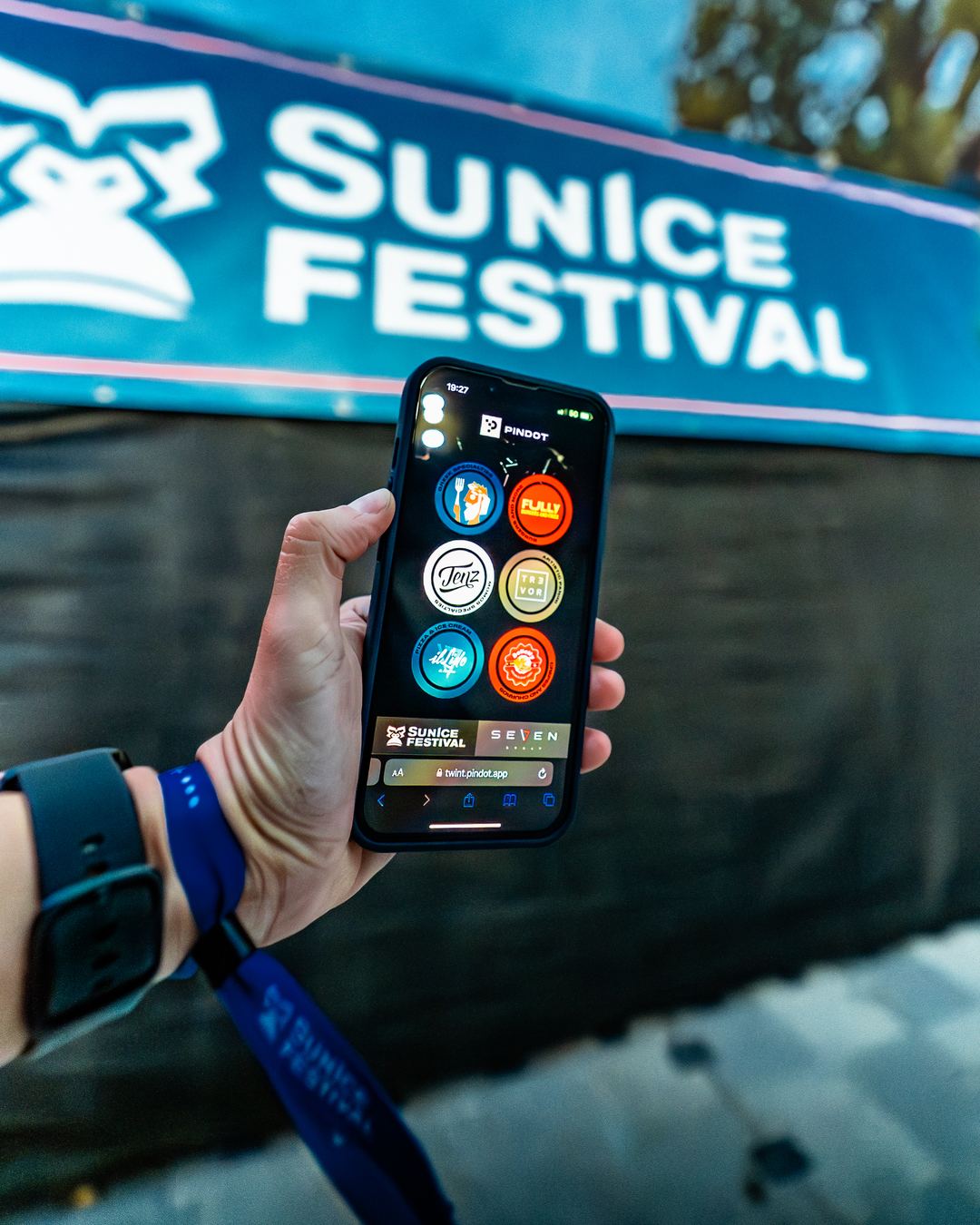 A phone in front of a screen showing the Sunice Festival name.