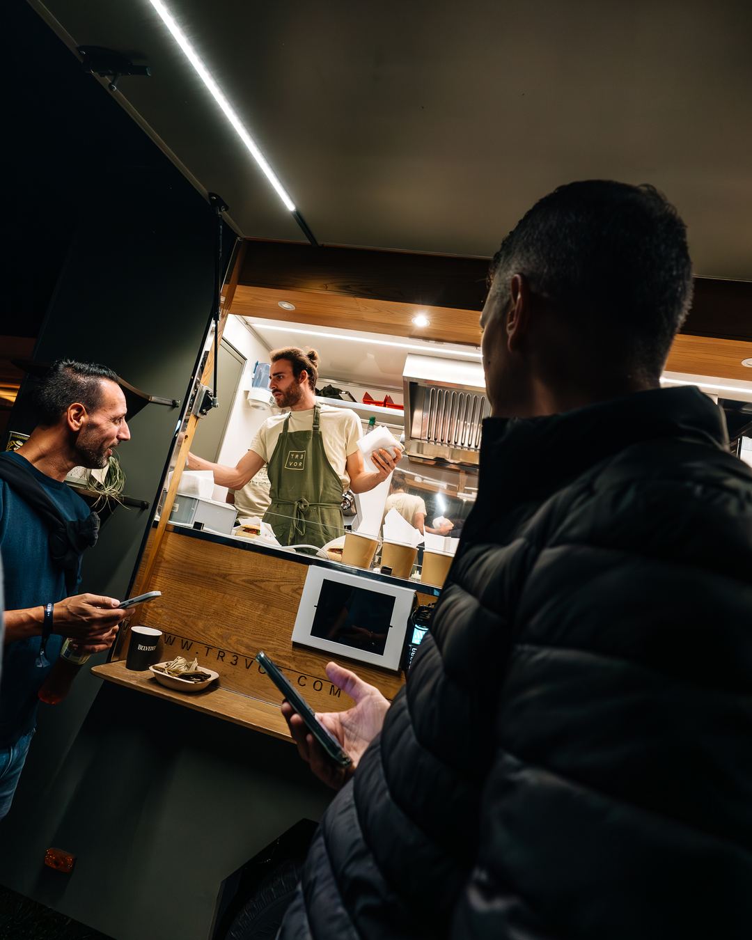 A guest orders at an indoor counter while staff prepare the order behind it.